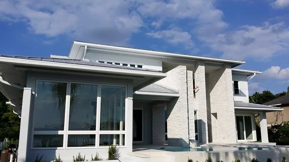 White contemporary home standing seam roof stacked stone pool fascia gutter sanf